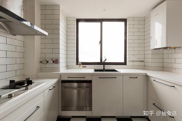 厨房米色的橱柜和台面相互搭配,墙上铺着小块白色瓷砖,看起来很清新