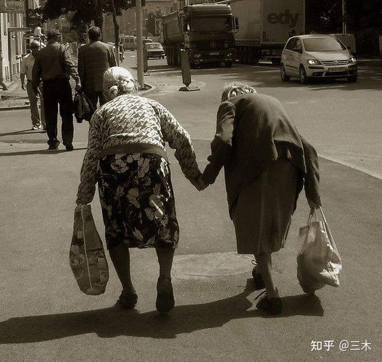 图为两位老奶奶在手牵手互相帮扶着过马路,人生有此友,足矣.