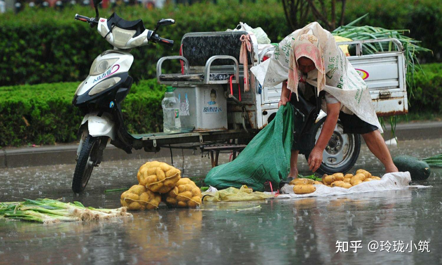 布,头上带着防雨帽,坐在一张小板凳上,询问着过往的路人要不要买菜