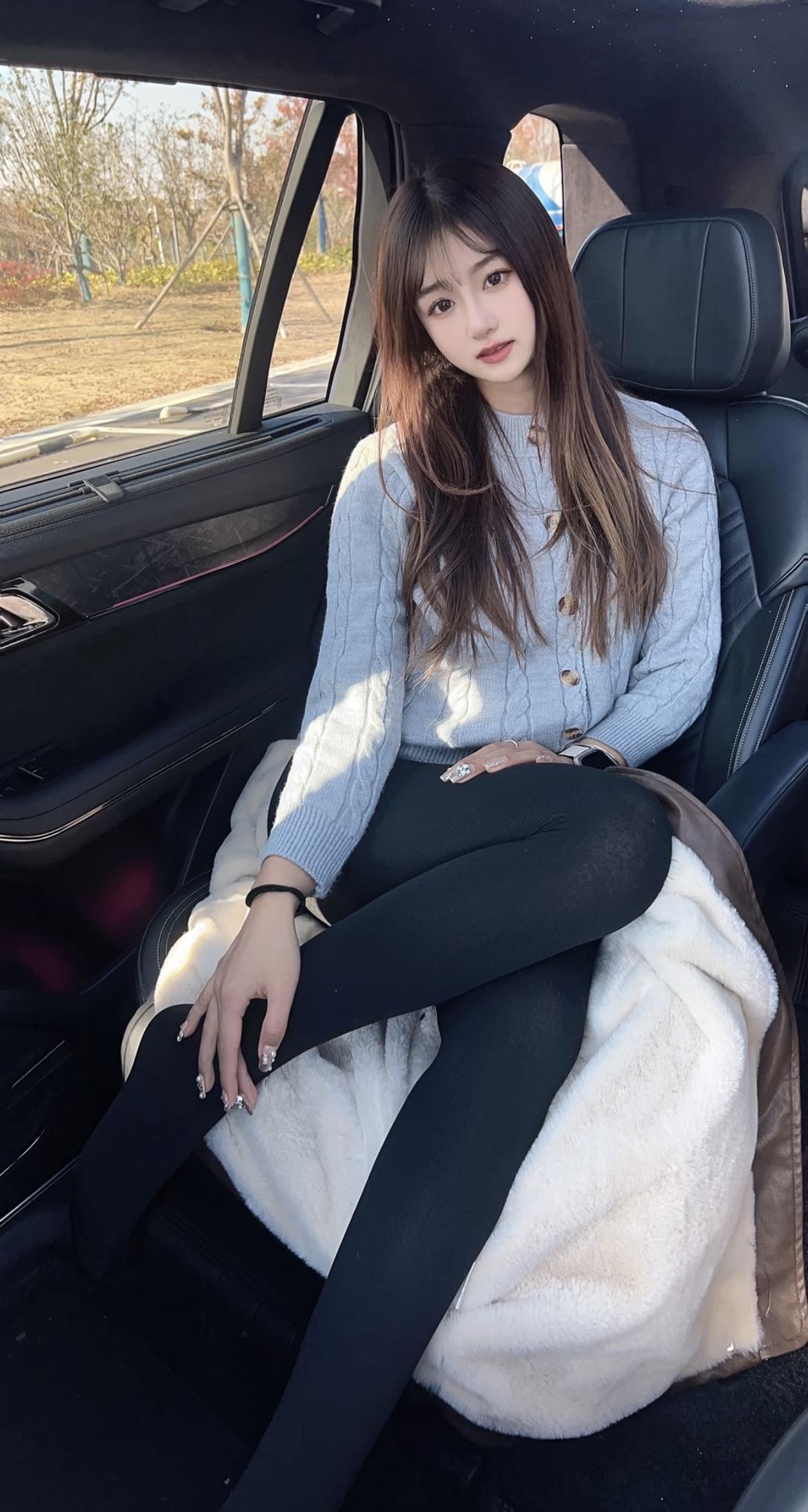 坐在车后座的女孩微笑中透露着无法言喻的幸福这件毛衣的温暖紧身裤的
