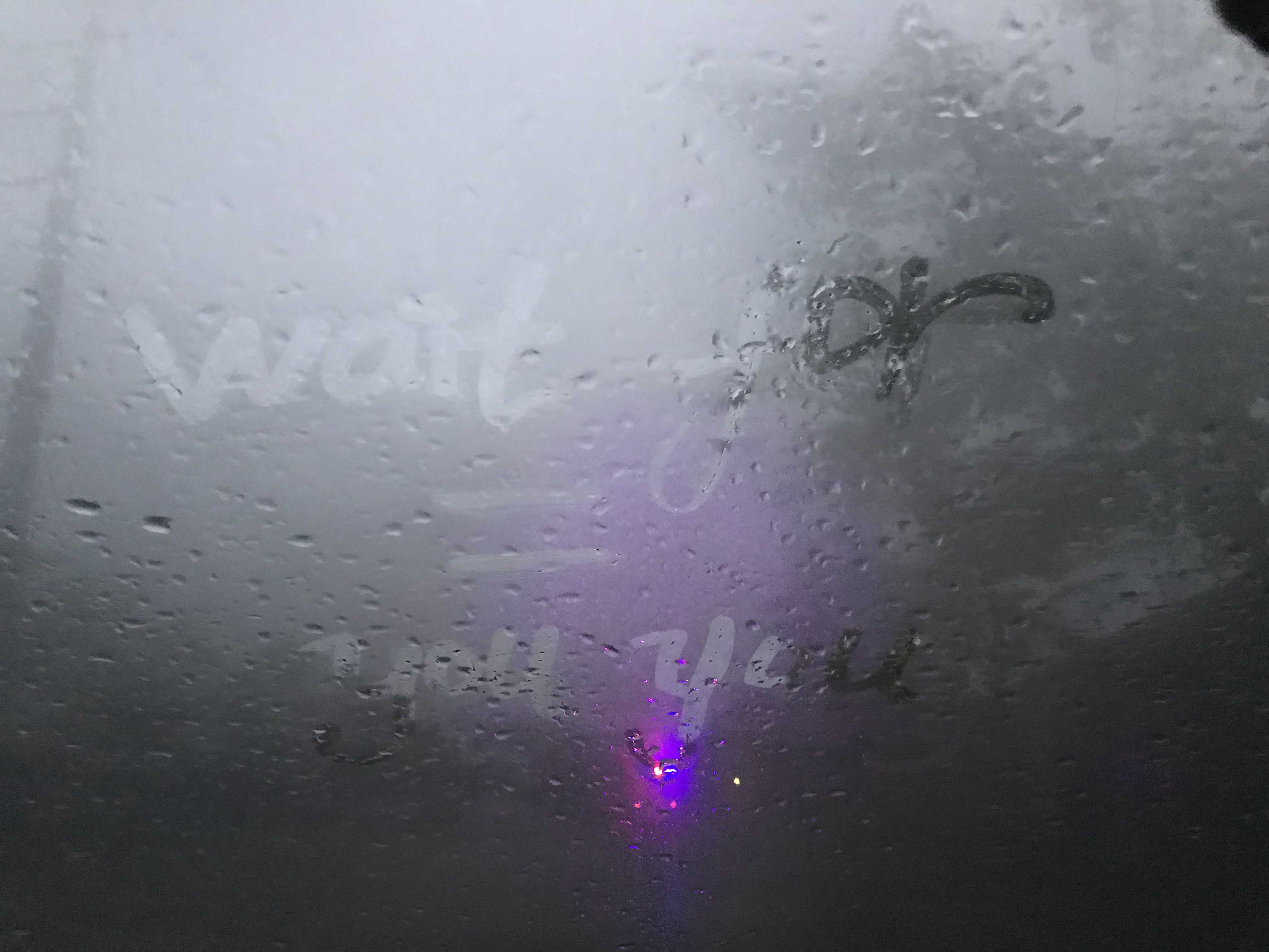 车外下着毛毛细雨,前挡风内玻璃上都是雾气,在玻璃还有一些小雨珠,看