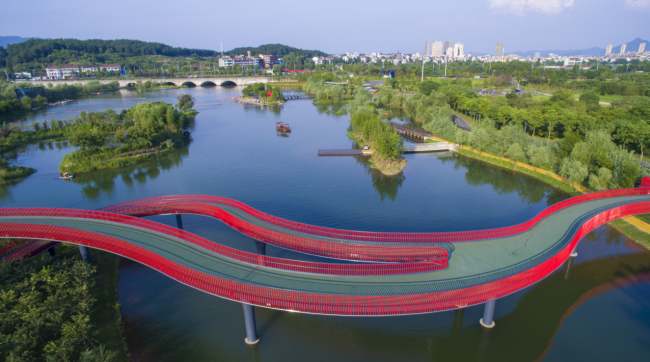 近处的水面波光粼粼,远处的山上郁郁葱葱,行走在金华浦江的翠湖彩虹桥