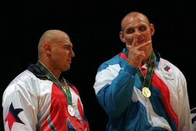 卡列林在领奖台上用手比划着"第三块金牌",一旁是望着偶像表情苦涩的